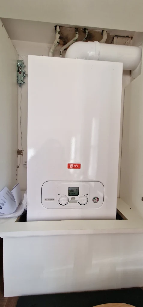 New wall-hung combi boiler installed and running inside a fitted kitchen cupboard