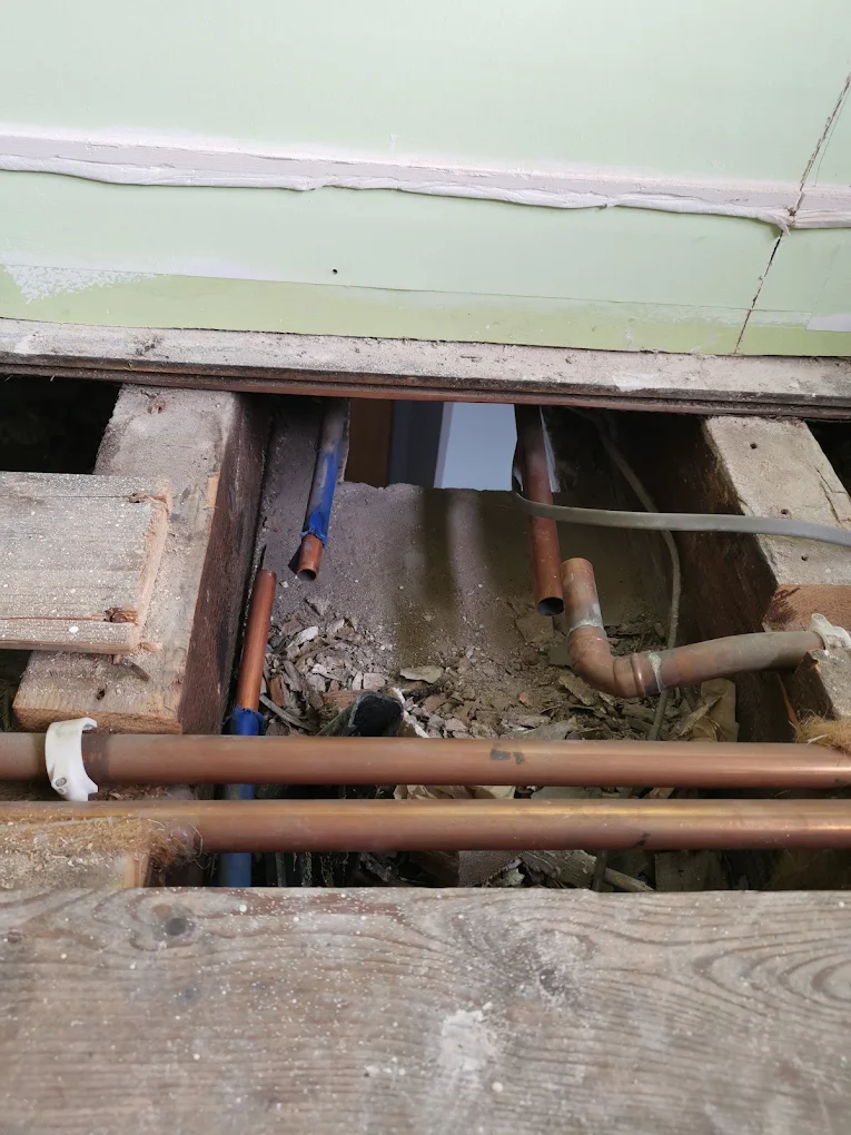 Copper heating pipework run between joists beneath a lifted floor
